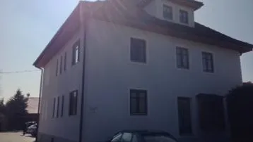 Helles Einfamilienhaus mit klassischer Architektur und Satteldach unter strahlendem Himmel.