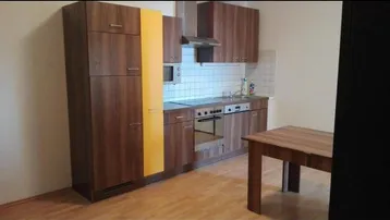 Funktionale Küche mit Holzschränken, gelbem Kühlschrank und Esstisch in einem hellen Raum.