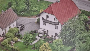 Luftaufnahme zweier Häuser mit gepflegten Gärten, Zufahrt und Außenbereich mit Pergola.