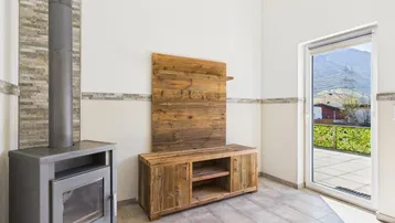 Gemütlicher Wohnbereich mit Kaminofen, Holzelementen und großem Fenster mit Bergblick.