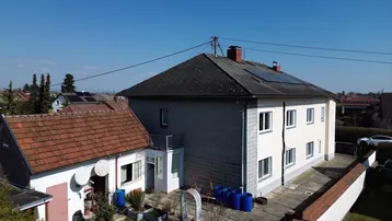 Luftaufnahme des Hauses mit angrenzendem Nebengebäude, Garten und Solaranlage auf dem Dach.