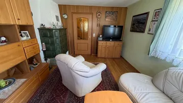 Gemütliches Wohnzimmer mit traditionellem Kachelofen, Holzvertäfelung und bequemen Sesseln.