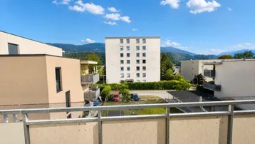 Weitblick vom Balkon über die umliegende Wohngegend und die dahinterliegenden Berge.