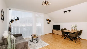 Helles Wohn-Esszimmer mit Holzboden, gemütlichem Sofa und Zugang zum Balkon.