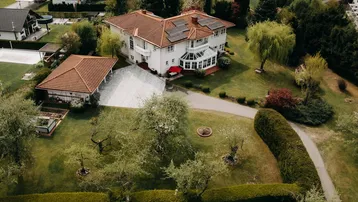 Luftaufnahme des Anwesens mit großem Garten, Photovoltaikanlage auf dem Dach und umliegender Landschaft.