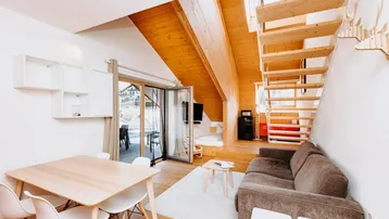 Helles Wohn- und Esszimmer mit Holzbalkendecke, Parkettboden und Zugang zur Terrasse.