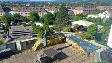 Große Dachterrasse mit Sitzgelegenheiten, Holzstapeln und weitem Blick über die Stadt und Berge.