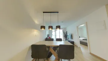 Moderner Essbereich mit Holztisch und dunklen Stühlen, offen zum Wohnzimmer.
