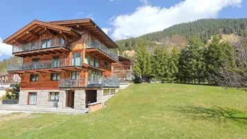 Großes Holzchalet mit mehreren Balkonen und Blick auf die umliegende Berglandschaft.