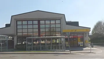 Außenansicht eines modernen Geschäftsgebäudes mit großen Fenstern und einer Postfiliale im Erdgeschoss.