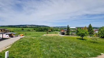 Weitläufige Grünfläche mit Blick auf die umliegende Landschaft und weitere Gebäude im Hintergrund.