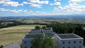 Luftaufnahme von Neubauten mit Photovoltaikanlagen auf den Dächern und weitem Blick über die Landschaft.