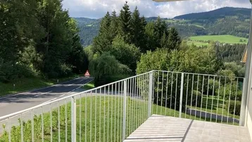 Balkon mit Fliesenboden und weitem Blick auf die grüne Landschaft und Berge.