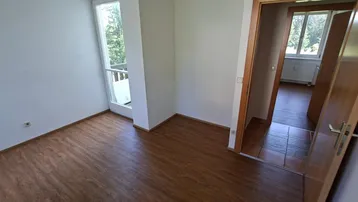Helles Zimmer mit Laminatboden und Zugang zu einem französischen Balkon, ideal für frische Luft.