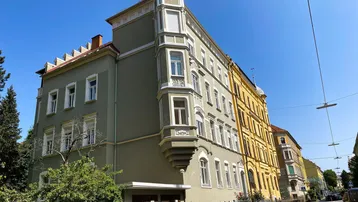 Historisches Mehrfamilienhaus mit markantem Erker und traditioneller Architektur in einer städtischen Umgebung.