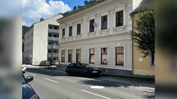 Historisches Gebäude mit klassischer Fassade und Blick auf die Straße sowie umliegende Häuser.