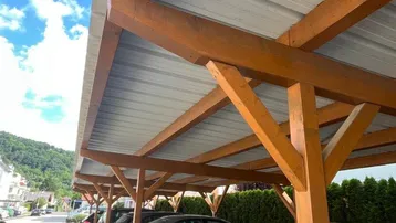 Überdachte Parkplätze unter einem Holzcarport mit Blick auf die umliegenden Berge.