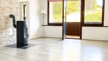 Helles Wohnzimmer mit modernem Kaminofen, Steinwandakzent und hellem Laminatboden.