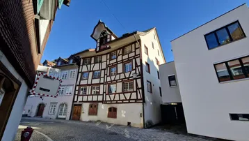 Historisches Fachwerkhaus in einer charmanten Gasse mit Kopfsteinpflaster unter blauem Himmel.