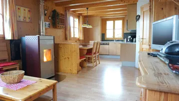 Offener Wohnbereich mit Holzboden, Kaminofen und integrierter Küche im Landhausstil.