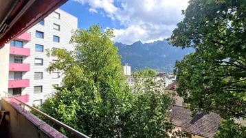 Balkon mit Bergblick und Aussicht auf die umliegende Stadt und grüne Bäume.