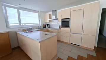 Moderne Einbauküche mit hellen Holzfronten, Kücheninsel und Fenster.