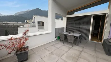 Geräumige Terrasse mit Esstisch und Stühlen, umgeben von einer beeindruckenden Bergkulisse.