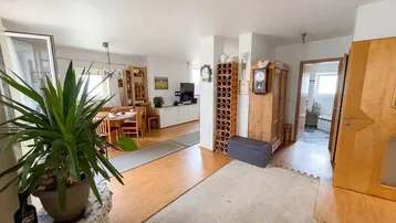 Geräumiger Wohn- und Essbereich mit Holzmöbeln, Holzboden und einem Weinflaschenregal.