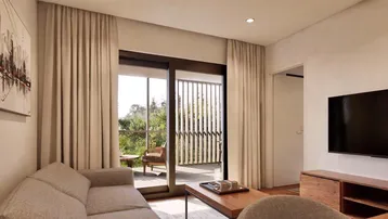 Helles Wohnzimmer mit beigem Sofa, Fernseher und großem Schiebetürzugang zu einem Außenbereich.