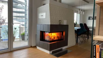 Heller Wohnbereich mit modernem Kaminofen, Holzboden und Zugang zu einer Außentreppe.