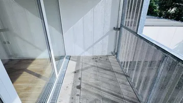 Heller Balkon mit Fliesenboden und Blick auf die umliegende grüne Landschaft.