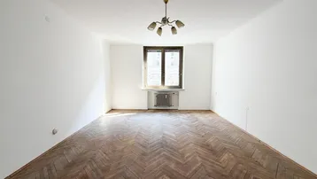 Helles Zimmer mit Fischgrätparkettboden, weißen Wänden und einem Fenster, bereit zur individuellen Gestaltung.