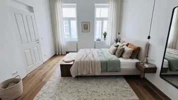 Helles Schlafzimmer mit Holzboden, großem Bett und moderner Einrichtung, durchflutet von natürlichem Licht.