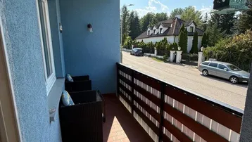 Blauer Balkon mit Terrakotta-Fliesen, Sitzgelegenheiten und Blick auf die Straße.