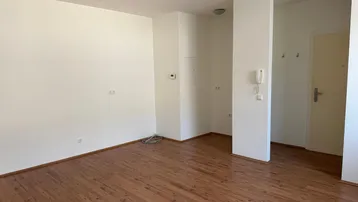 Helles, leeres Wohnzimmer mit Laminatboden und weiß gestrichenen Wänden, bereit zur Einrichtung.