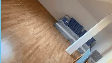 Helles Schlafzimmer im Dachgeschoss mit Holzboden und schrägen Wänden, ideal für gemütliches Wohnen.