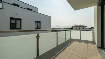 Heller Balkon mit Glasbrüstung und Blick auf die umliegenden Gebäude und Landschaft.
