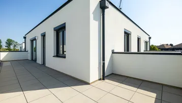 Große, sonnige Dachterrasse mit modernen Fliesen und Blick auf die Umgebung.