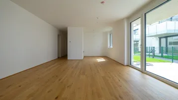 Helles, leeres Wohnzimmer mit modernem Eichenparkett und Zugang zur Terrasse.