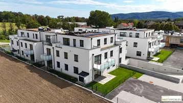 Neubau-Apartmentkomplex mit moderner Architektur, Balkonen und Photovoltaikanlagen auf den Dächern.