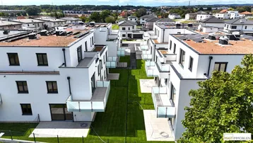 Moderne Wohnanlage mit mehreren Gebäuden, begrünten Flachdächern und privaten Gärten.