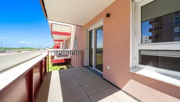 Geräumiger Balkon mit Fliesenboden und Blick auf die umliegenden Gebäude und Grünflächen.