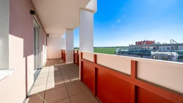 Geräumiger Balkon mit Fliesenboden und weitem Blick über grüne Felder und die Umgebung.