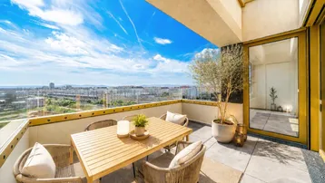 Große, sonnige Terrasse mit modernen Gartenmöbeln und weitem Blick über die Stadt.