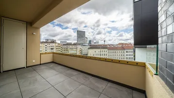 Geräumiger Balkon mit Fliesenboden und weitem Blick über die Stadtlandschaft und umliegende Gebäude.