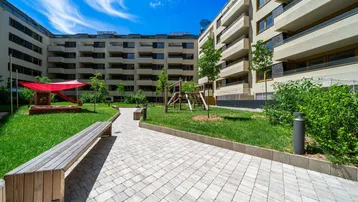 Grüner Innenhof mit Spielplatz und Sitzbänken, umgeben von modernen Wohngebäuden.