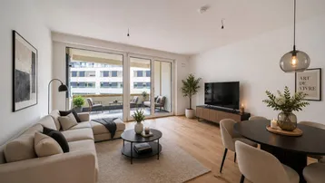 Modernes Wohn-Esszimmer mit hellem Parkettboden, bequemer Couch und Zugang zu einem Balkon.