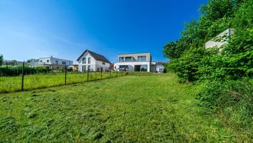 Großer, sonniger Gartenbereich mit gepflegtem Rasen und Blick auf moderne Wohnhäuser.