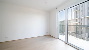 Helles, unmöbliertes Zimmer mit Parkettboden und großen Fenstern, die viel Tageslicht hereinlassen.