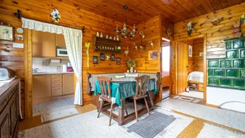 Gemütlicher Wohn-Essbereich mit Holztäfelung, traditionellem Kachelofen und rustikalen Möbeln.